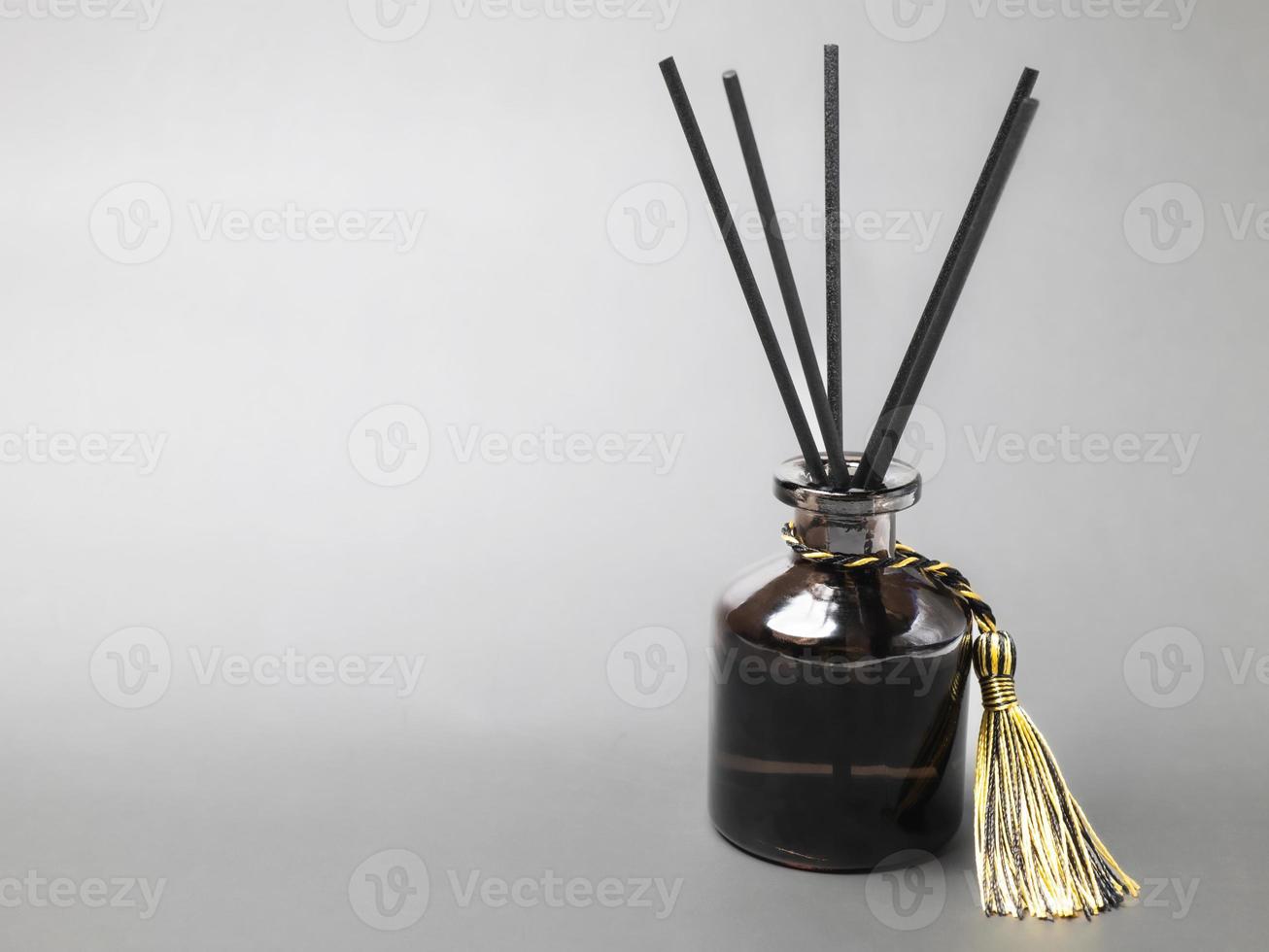 long black fragrant sticks one by one In a luxury opaque glass bottle with essential oils to spread the fragrance gray background There is a text area. photo