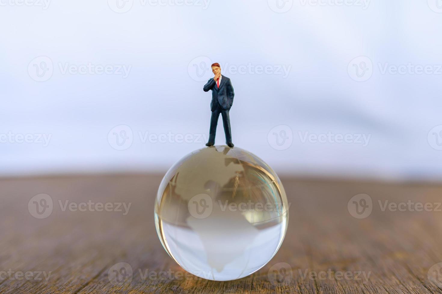 Global and Business Concept. Businessman miniature people figure standing on glass clear world ball model. photo