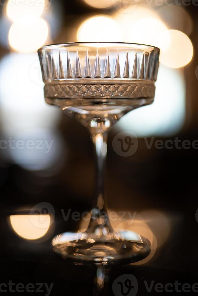 empty crystal glass on the bar with beautiful light and bokeh in the background. photo