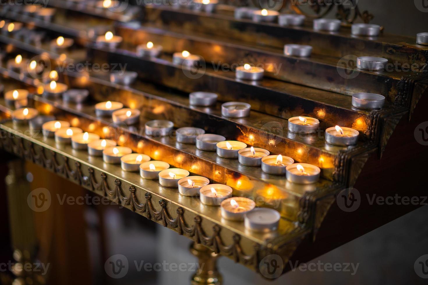 many fired candles in the church on a stand photo