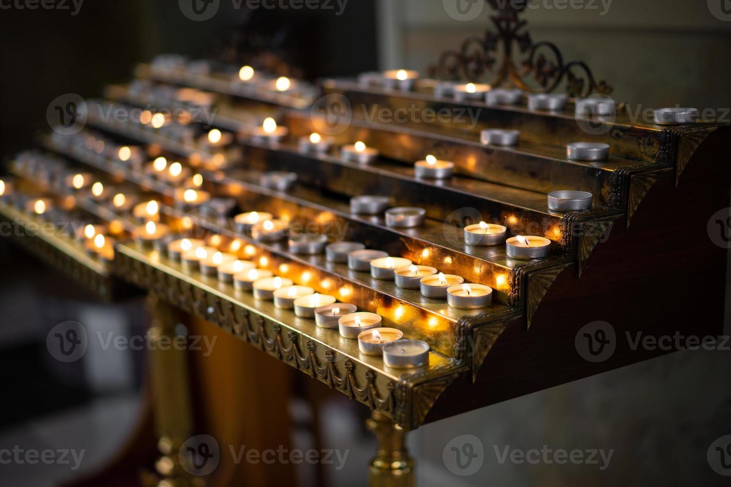 muchas velas encendidas en la iglesia en un stand foto