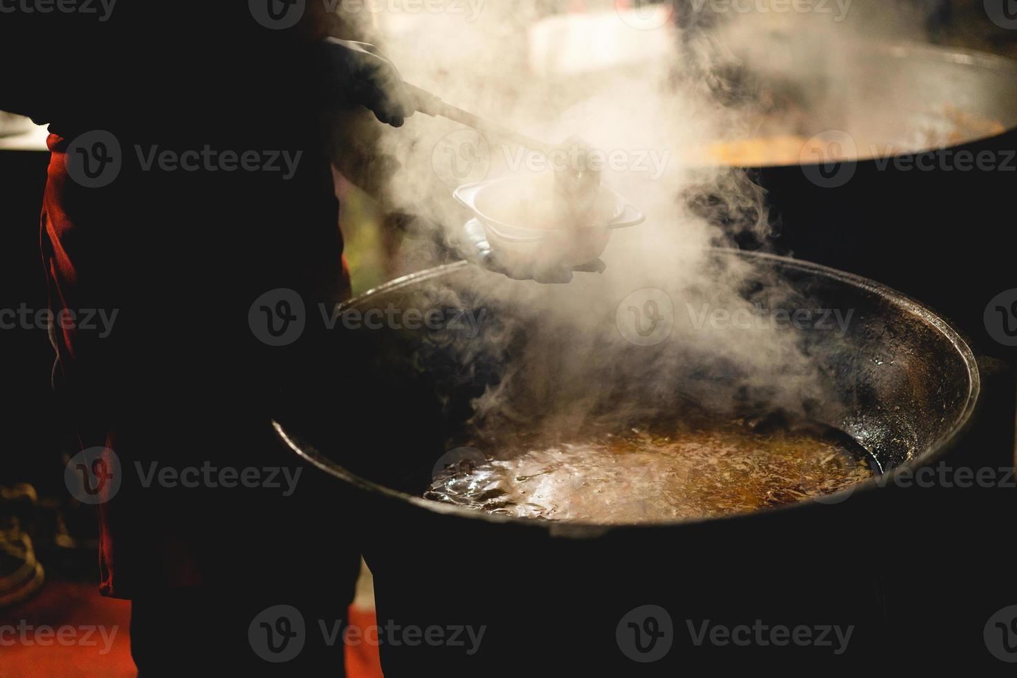 the cook fills a bowl with hot street food photo