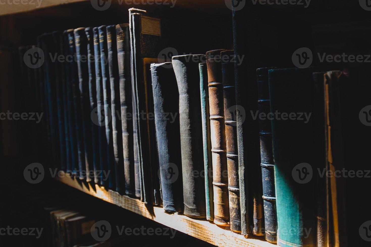 libros antiguos en la estantería de la biblioteca bajo el rayo del sol foto