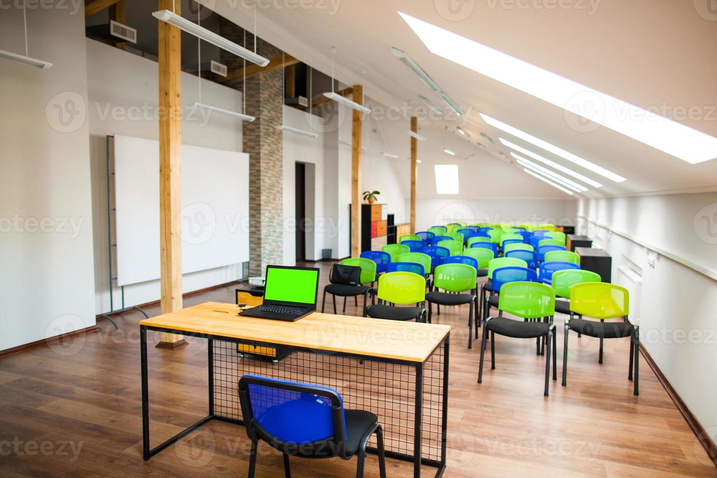 modern lecture room with with colored chairs and interesting design, laptop on the table, green screen photo