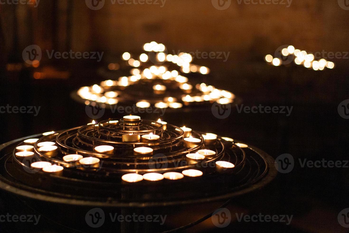 many fired candles in the church on a stand. photo