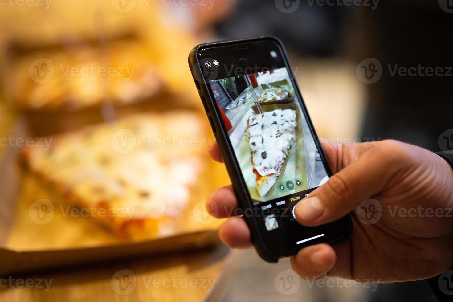 piece of pizza taking a photo on the phone