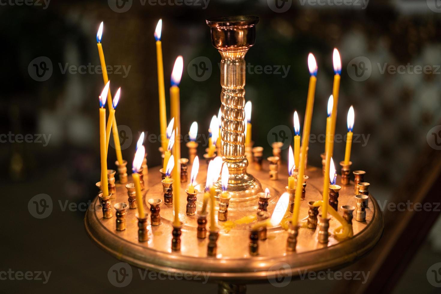 many fired candles in the church on a stand photo