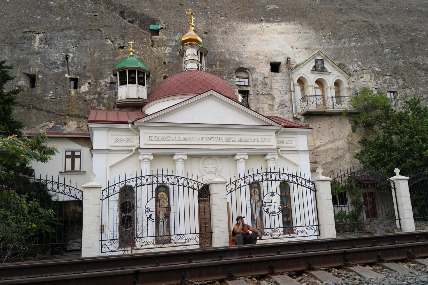 una iglesia en medio de una montaña de piedra rocosa cerca de una vía férrea en crimea, ucrania foto