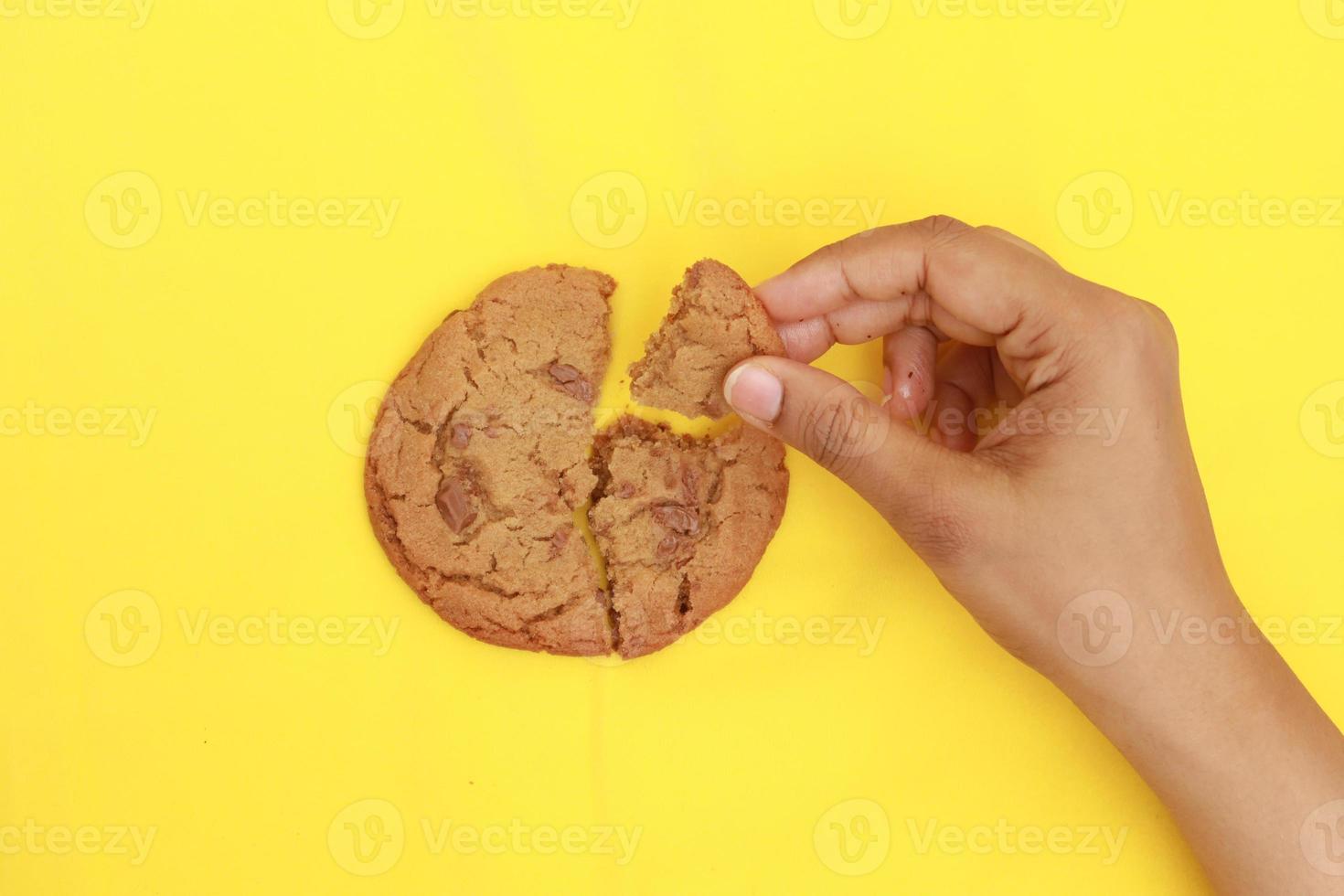 overhead view of breaking sweet cookies on yellow background photo