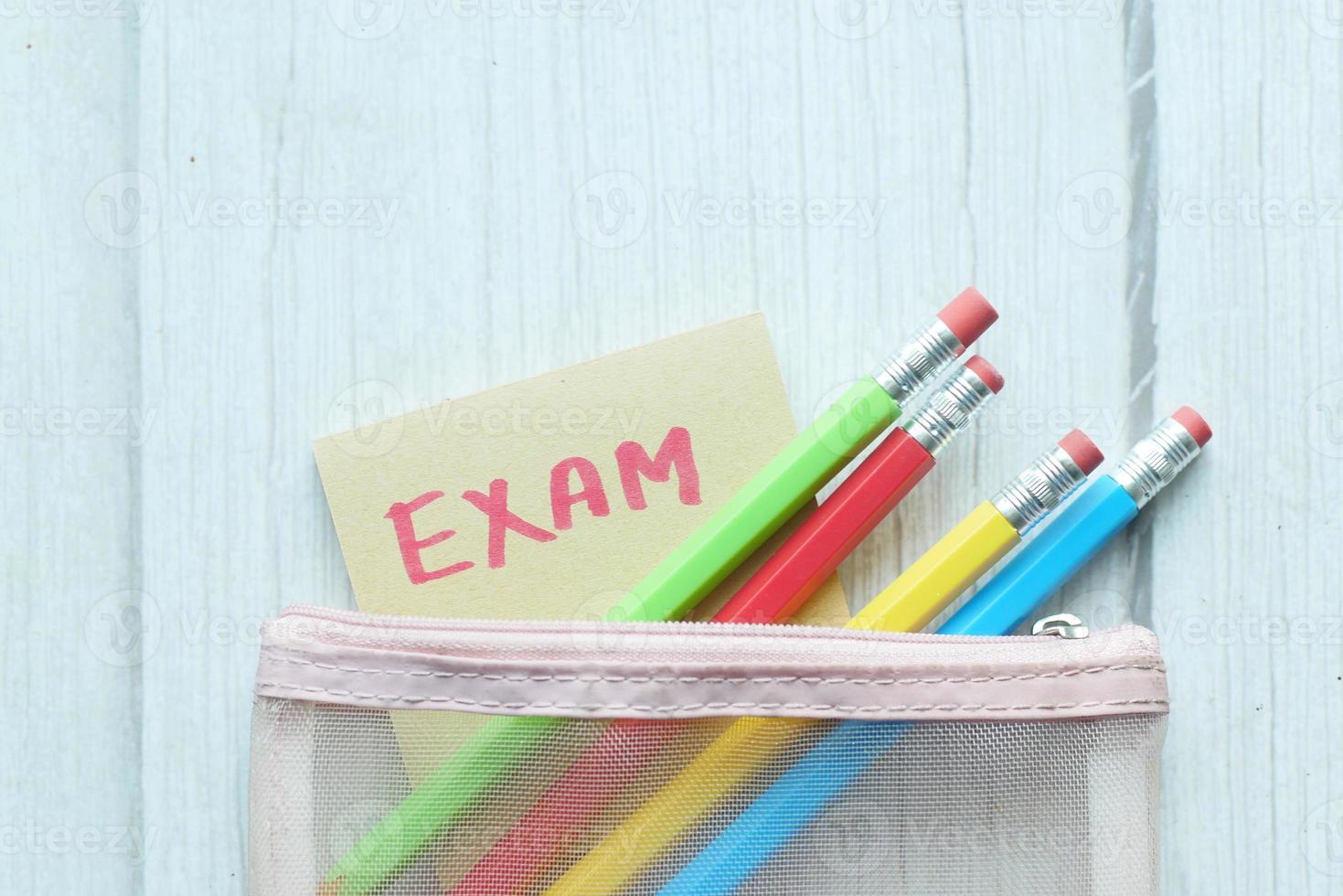 exam word in a sticky note and pencils on color background photo