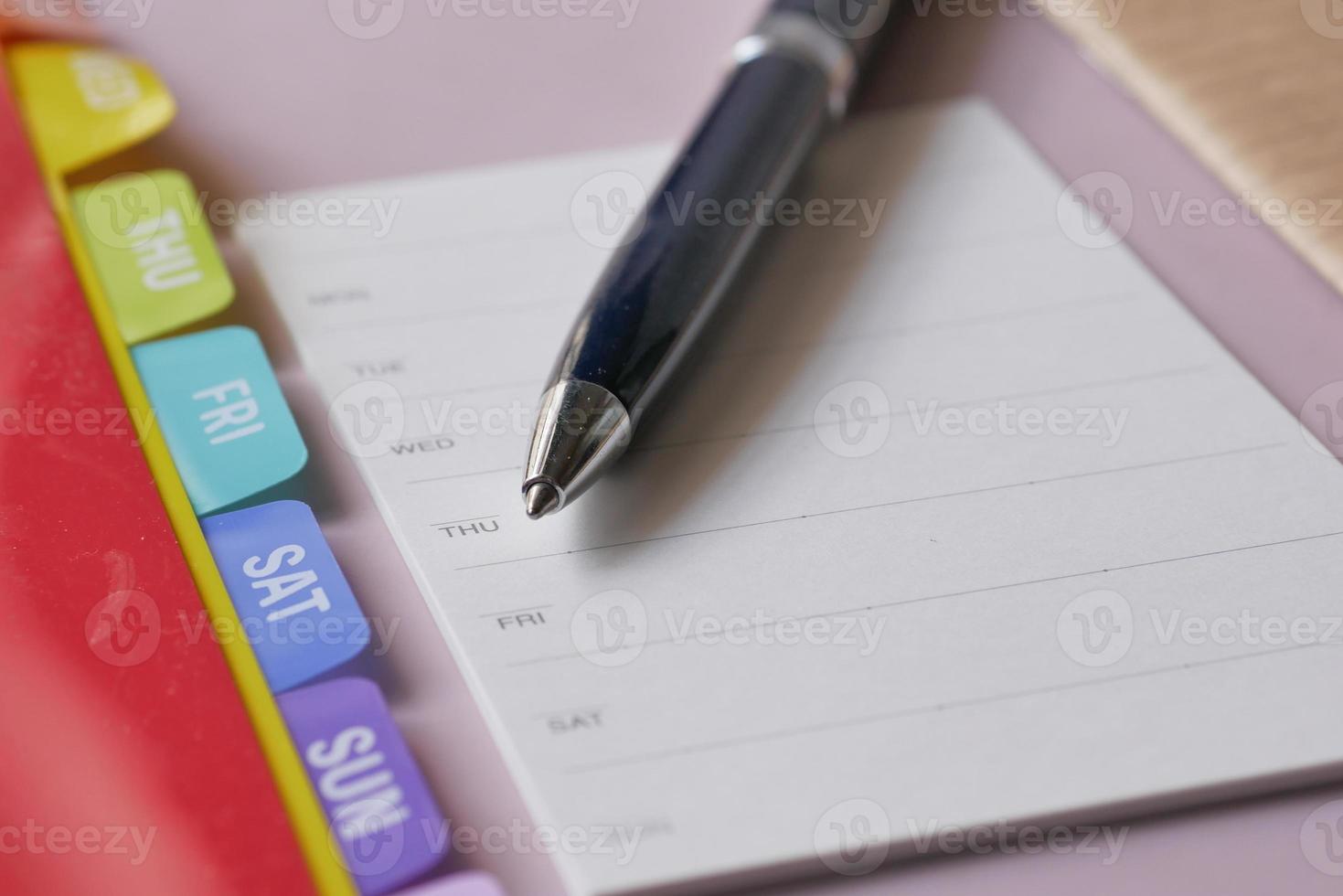 weekly planner and notepad on table photo