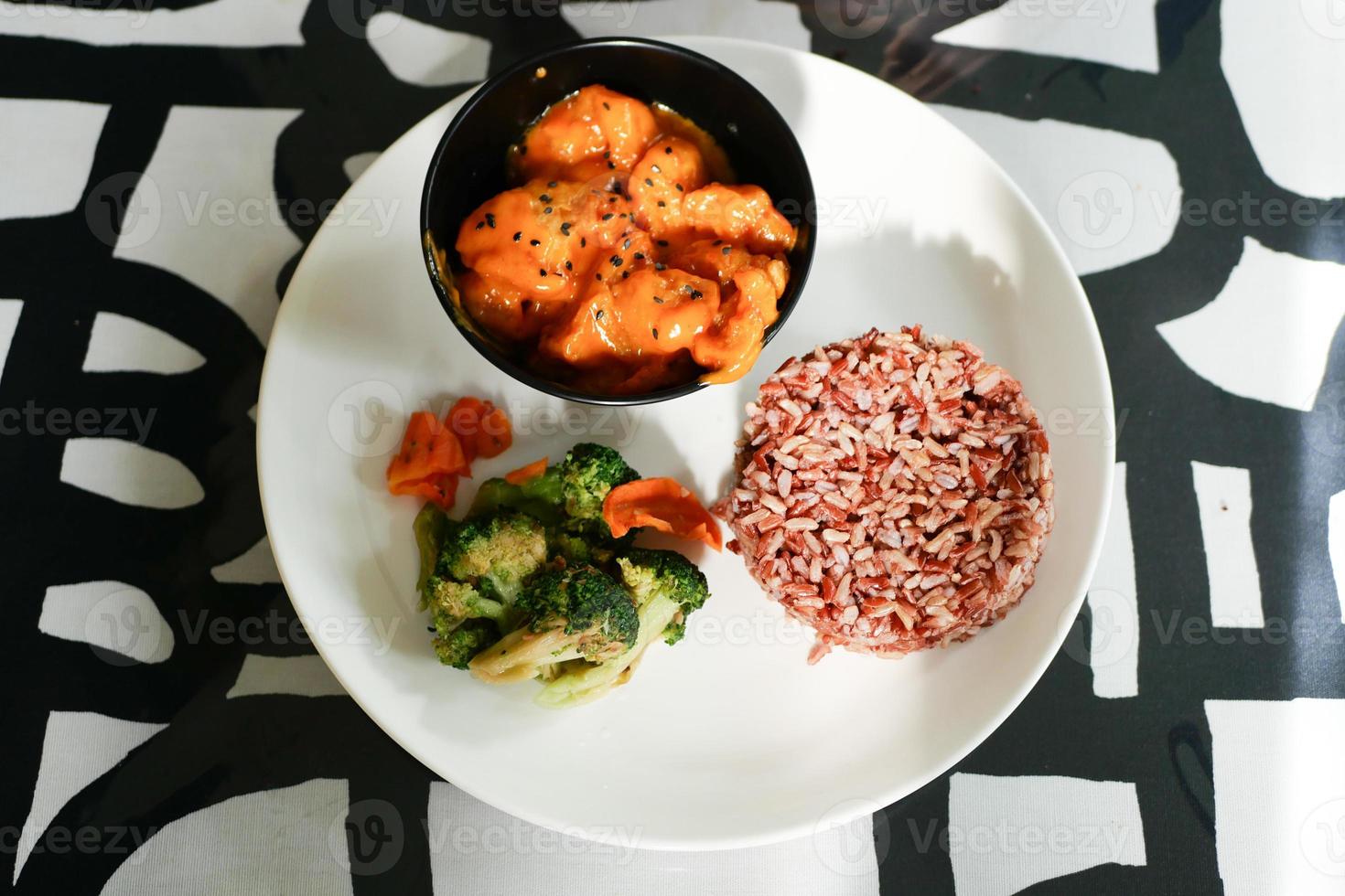 cooked red rice , vegetable salad and fish curry in a bowl on table photo