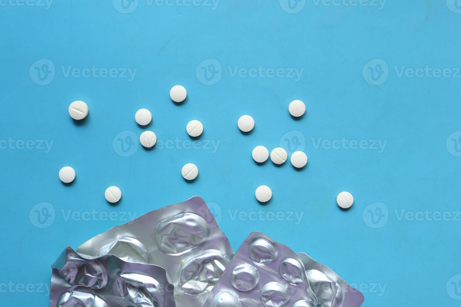 top view of blister pack and medicine spilling on blue photo