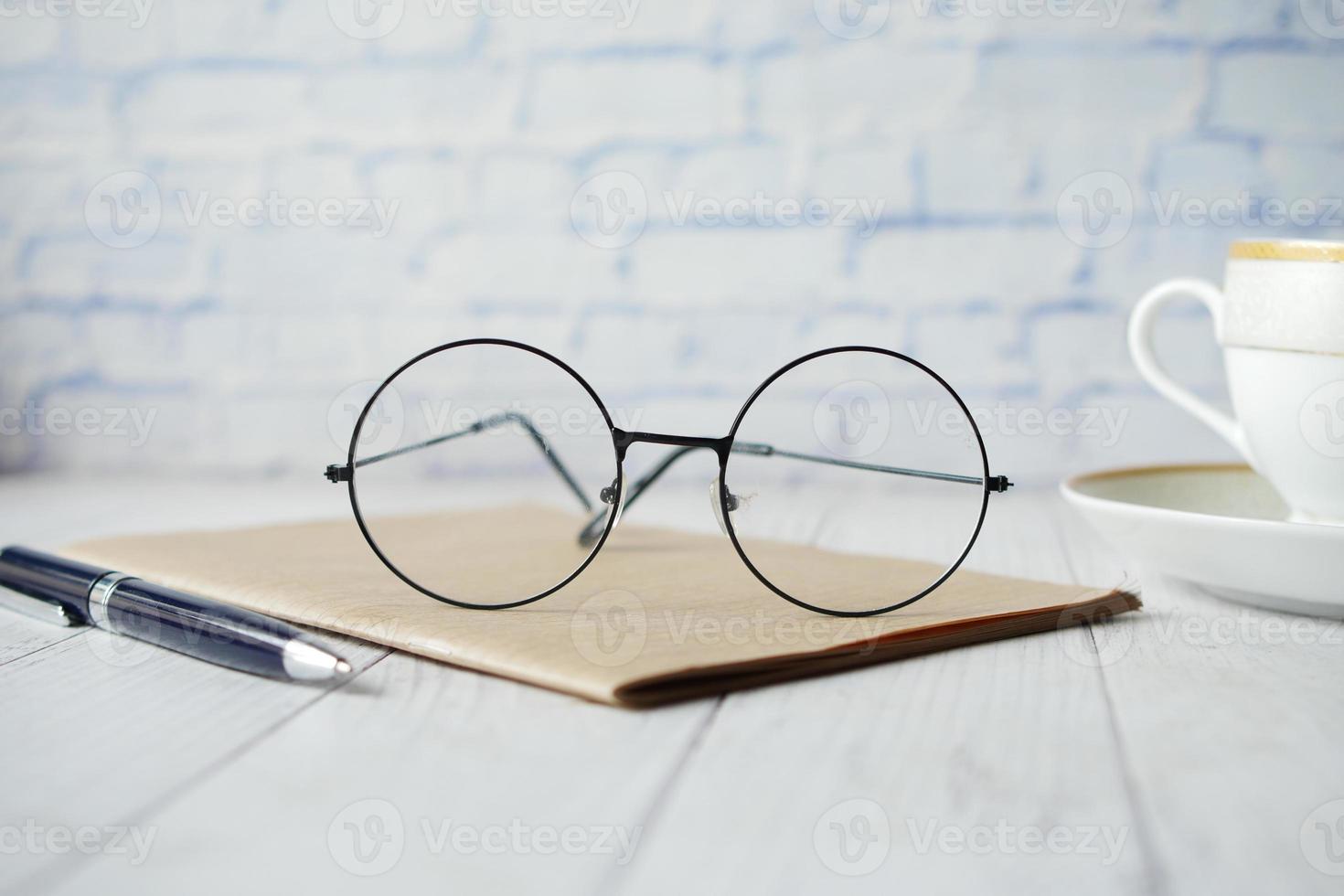 notepad, eyeglass and a pencil on wooden table photo