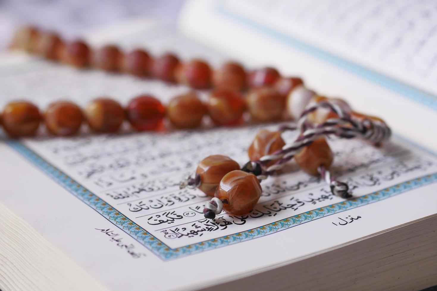 Holy book Quran and rosary on table, close up. photo