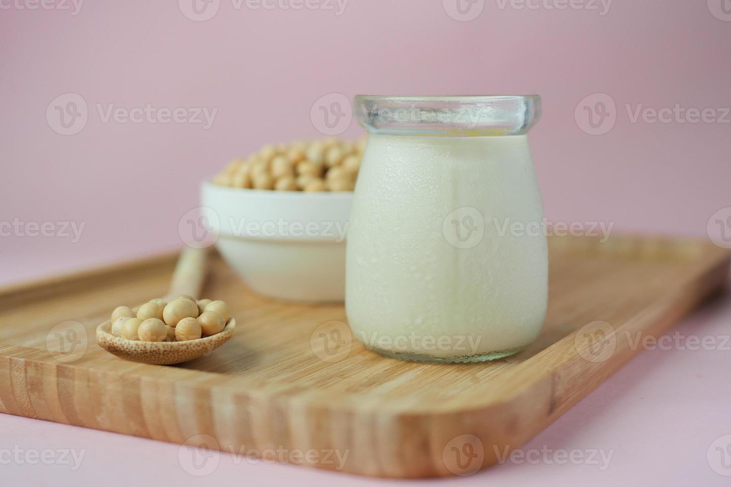 soy milk pouring in a glass jar on light pin background photo