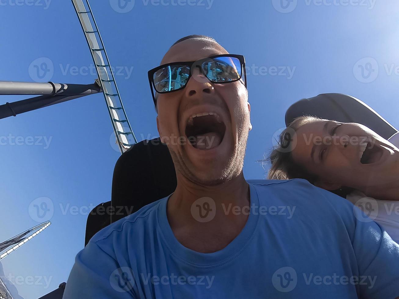 Man and woman on a roller coaster ride with emotion on their faces. photo