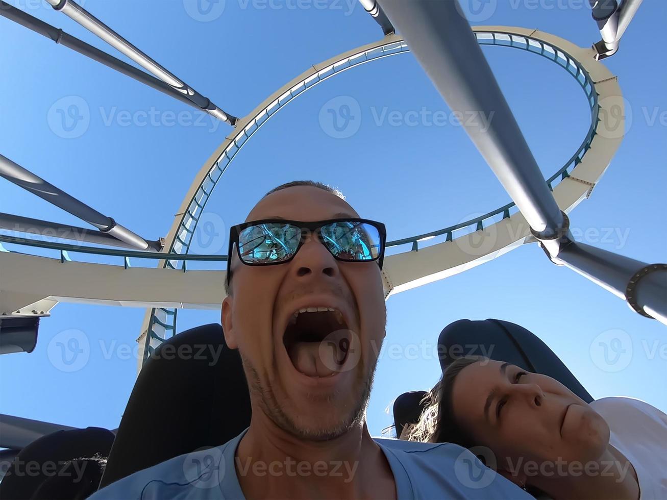 Man and woman on a roller coaster ride with emotion on their faces. photo