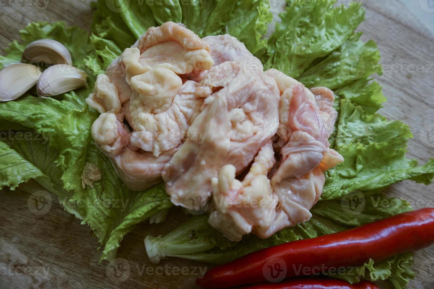Raw chicken skin on a chopping Board with lettuce, red chilies, and