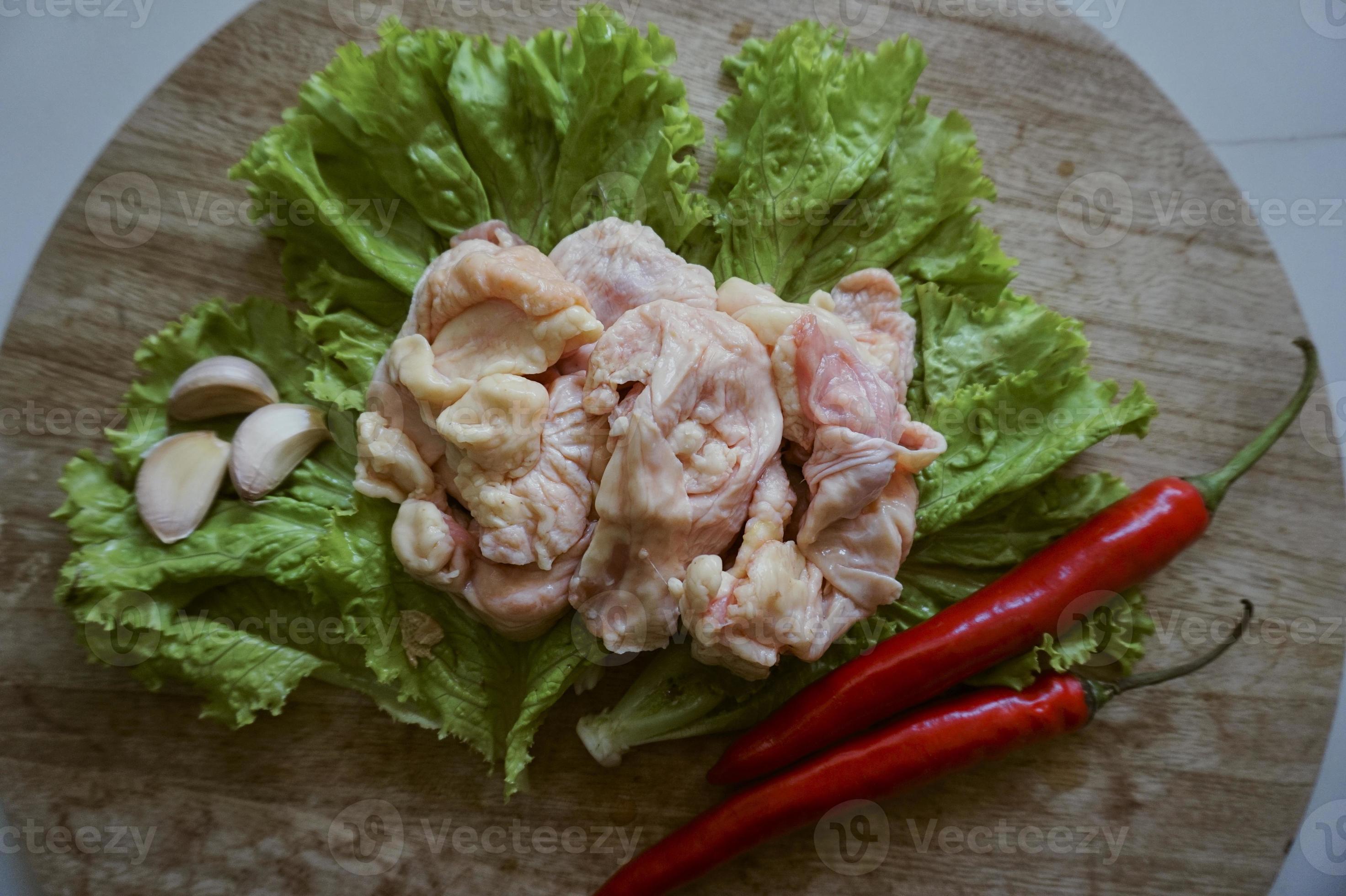 Raw chicken skin on a chopping Board with lettuce, red chilies, and