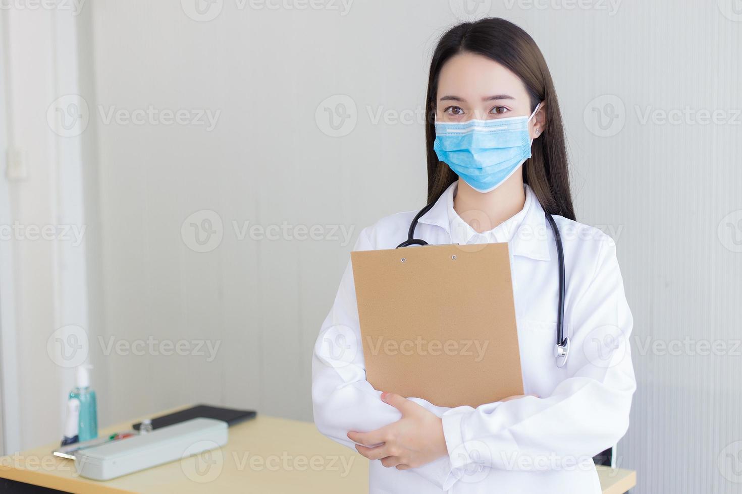 doctora asiática, que usa una bata blanca de laboratorio y una máscara quirúrgica. foto