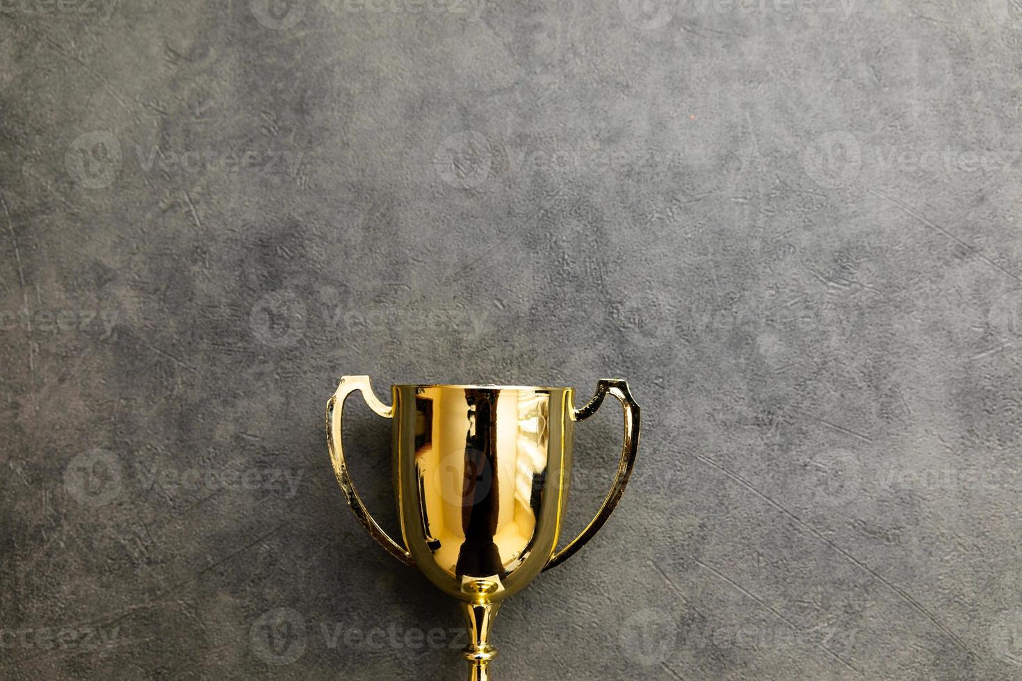 Simply flat lay design winner or champion gold trophy cup on concrete stone grey background. Victory first place of competition. Winning or success concept. Top view copy space. photo