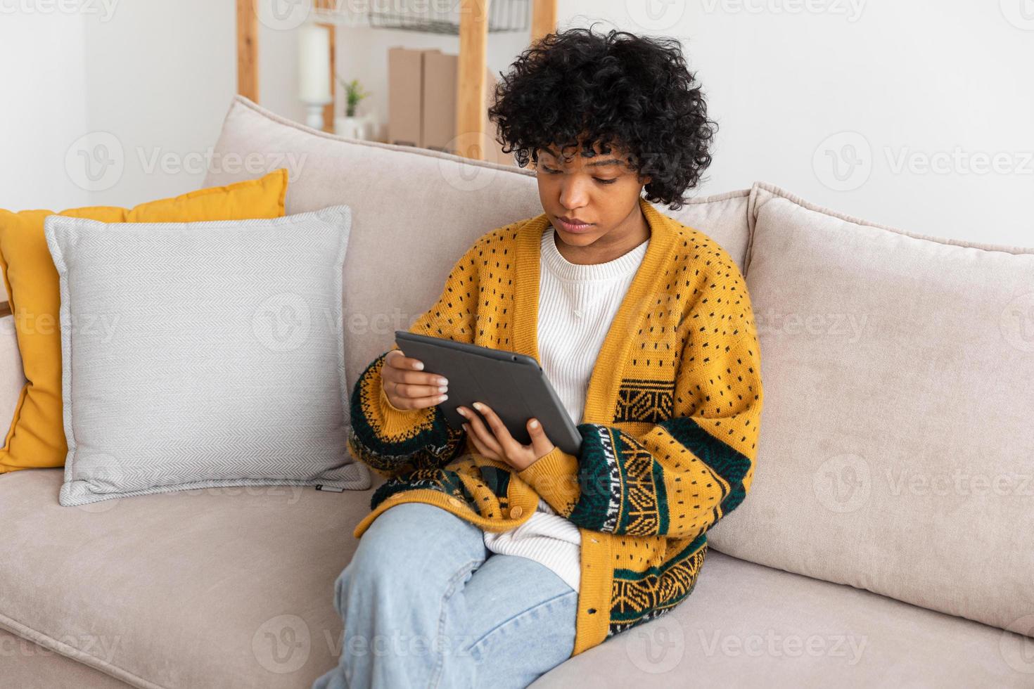 African american girl holding digital tablet touch screen typing scroll page at home. Woman with mobile tech device surfing internet using social media apps playing game. Study work shopping online. photo