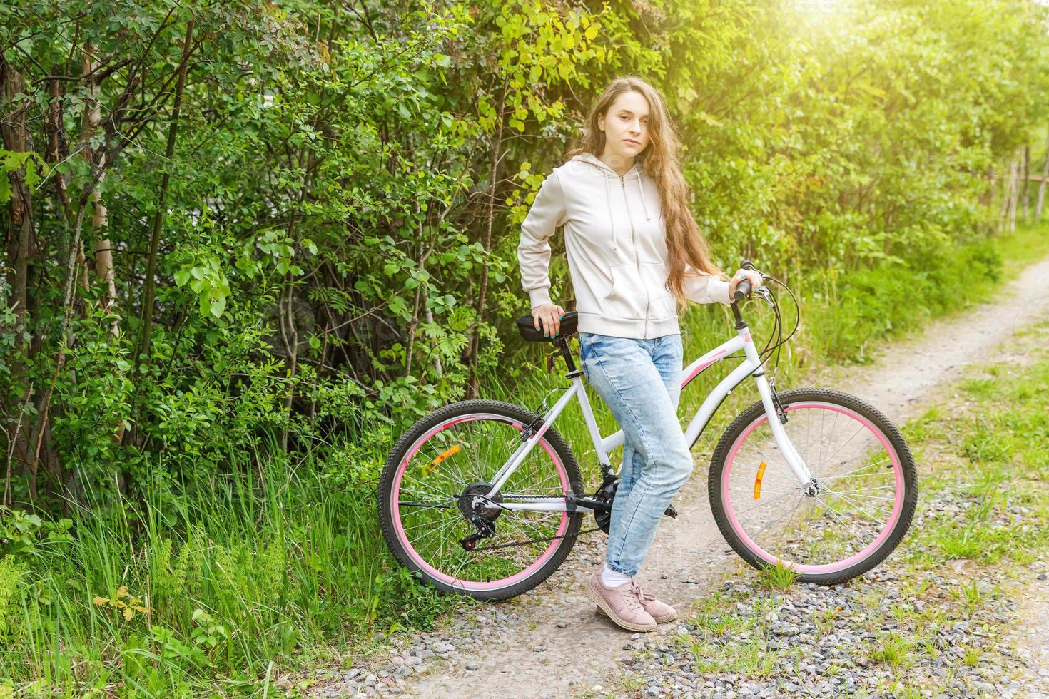 mujer joven montando en bicicleta en el parque de la ciudad de verano al aire libre. gente activa chica hipster relajarse y andar en bicicleta foto