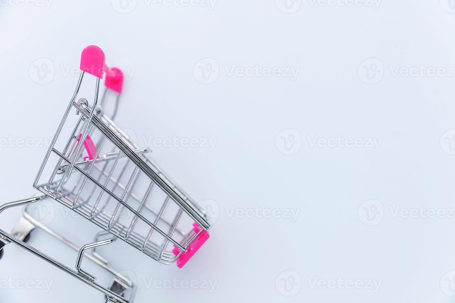 Small supermarket grocery push cart for shopping toy with wheels isolated on white background. Sale buy mall market shop consumer concept. Copy space. photo