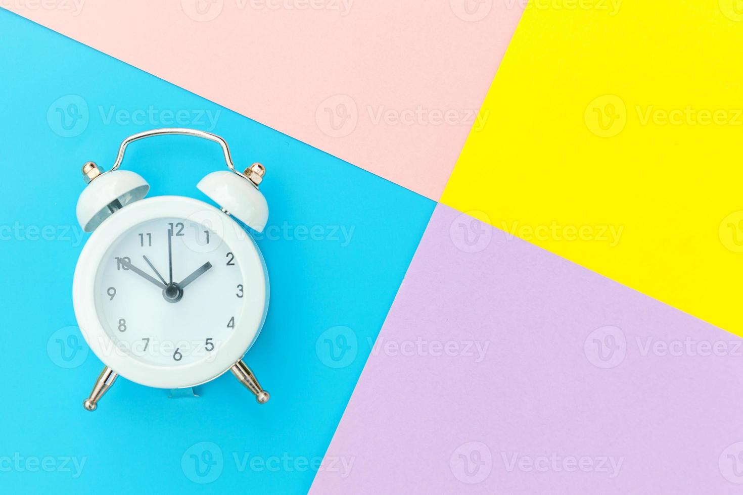 Ringing twin bell classic alarm clock isolated on blue yellow pink pastel colorful geometric background. Rest hours time of life good morning night wake up awake concept. Flat lay top view copy space. photo