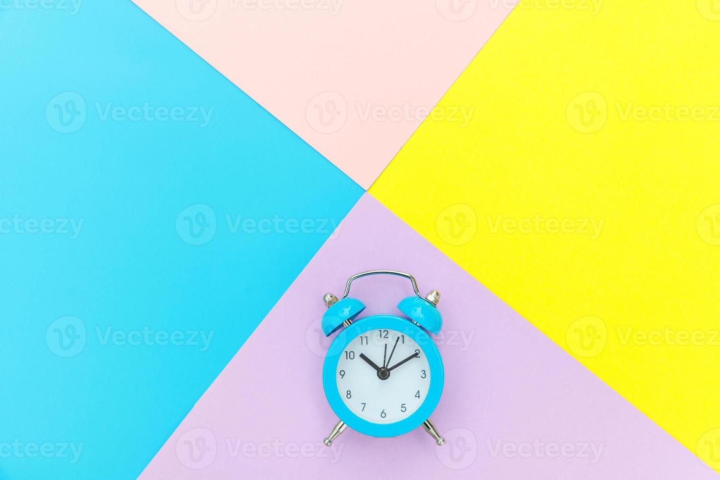 Ringing twin bell classic alarm clock isolated on blue yellow pink pastel colorful geometric background. Rest hours time of life good morning night wake up awake concept. Flat lay top view copy space. photo