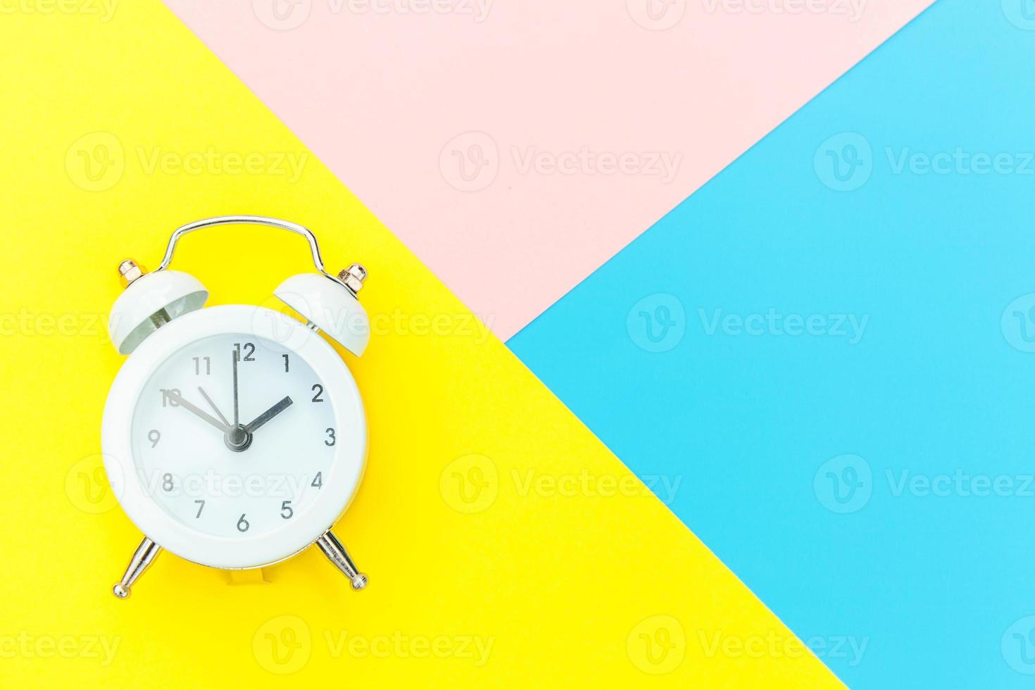 Ringing twin bell classic alarm clock isolated on blue yellow pink pastel colorful geometric background. Rest hours time of life good morning night wake up awake concept. Flat lay top view copy space. photo