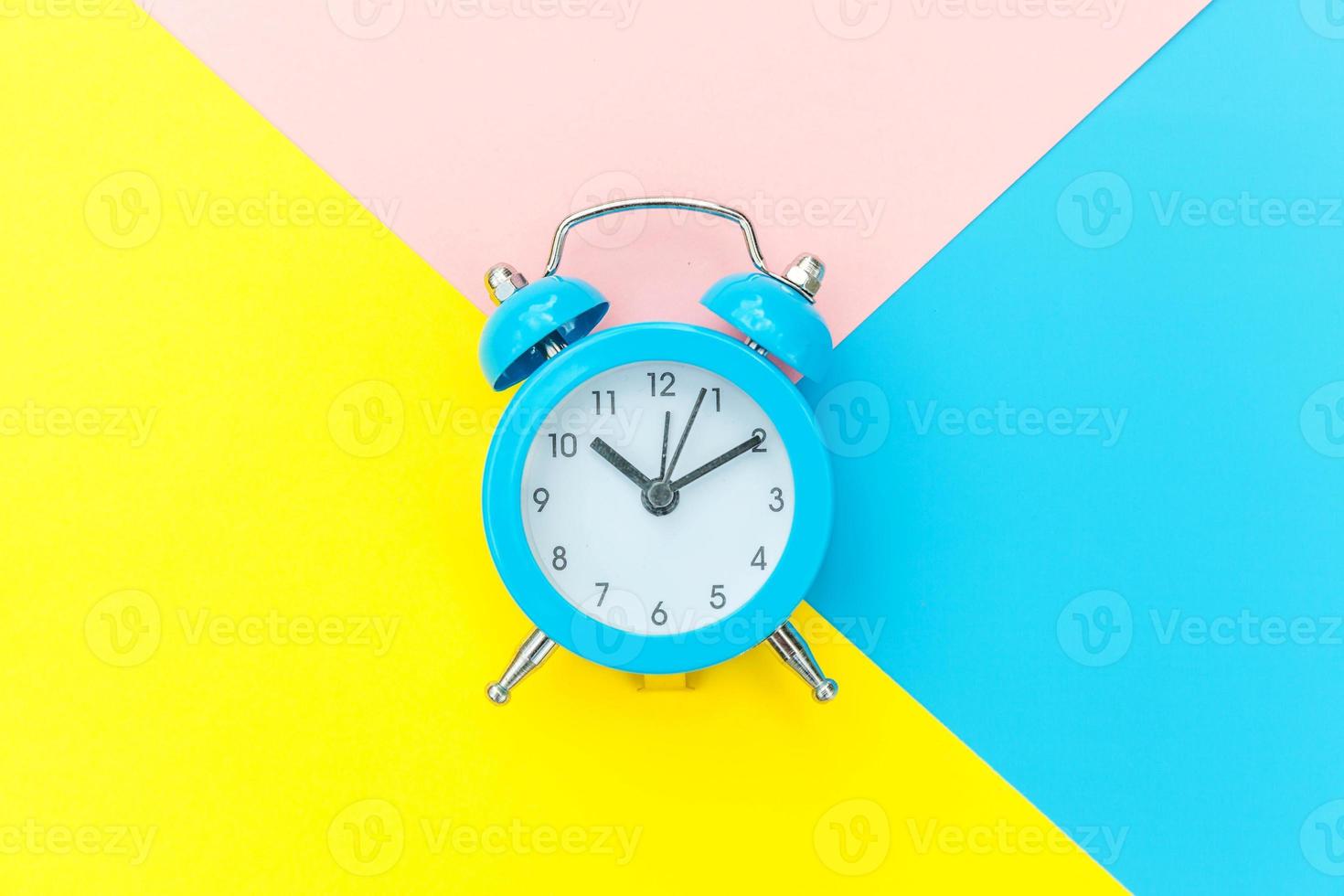 Ringing twin bell classic alarm clock isolated on blue yellow pink pastel colorful geometric background. Rest hours time of life good morning night wake up awake concept. Flat lay top view copy space. photo