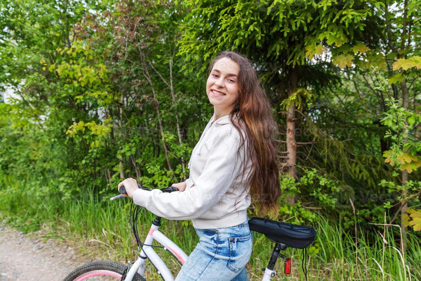 Young woman riding bicycle in summer city park outdoors. Active people. Hipster girl relax and rider bike photo