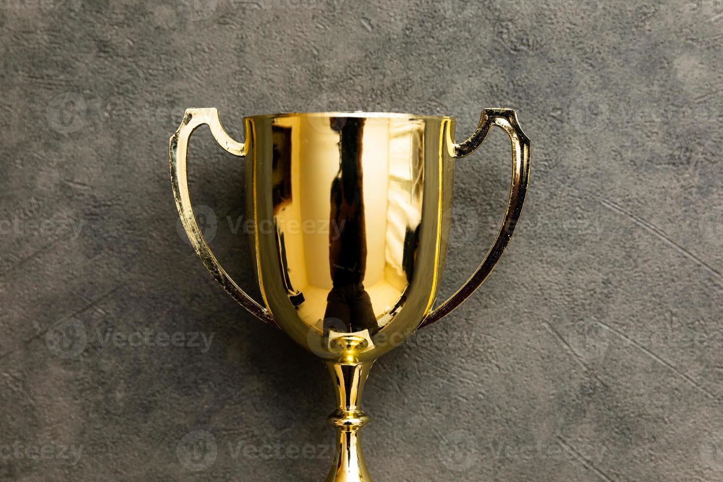 Simply flat lay design winner or champion gold trophy cup on concrete stone grey background. Victory first place of competition. Winning or success concept. Top view copy space. photo