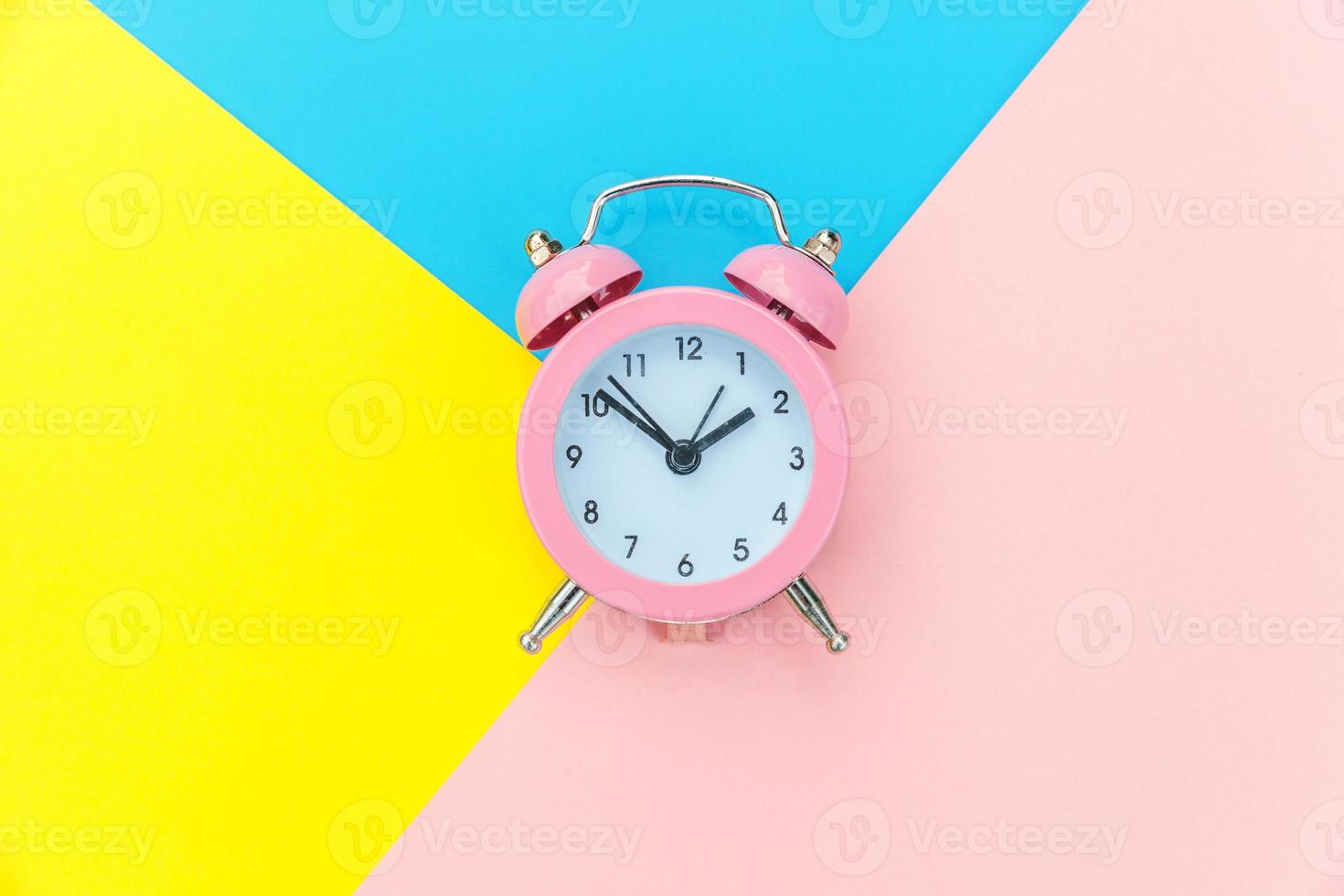 Ringing twin bell classic alarm clock isolated on blue yellow pink pastel colorful geometric background. Rest hours time of life good morning night wake up awake concept. Flat lay top view copy space. photo