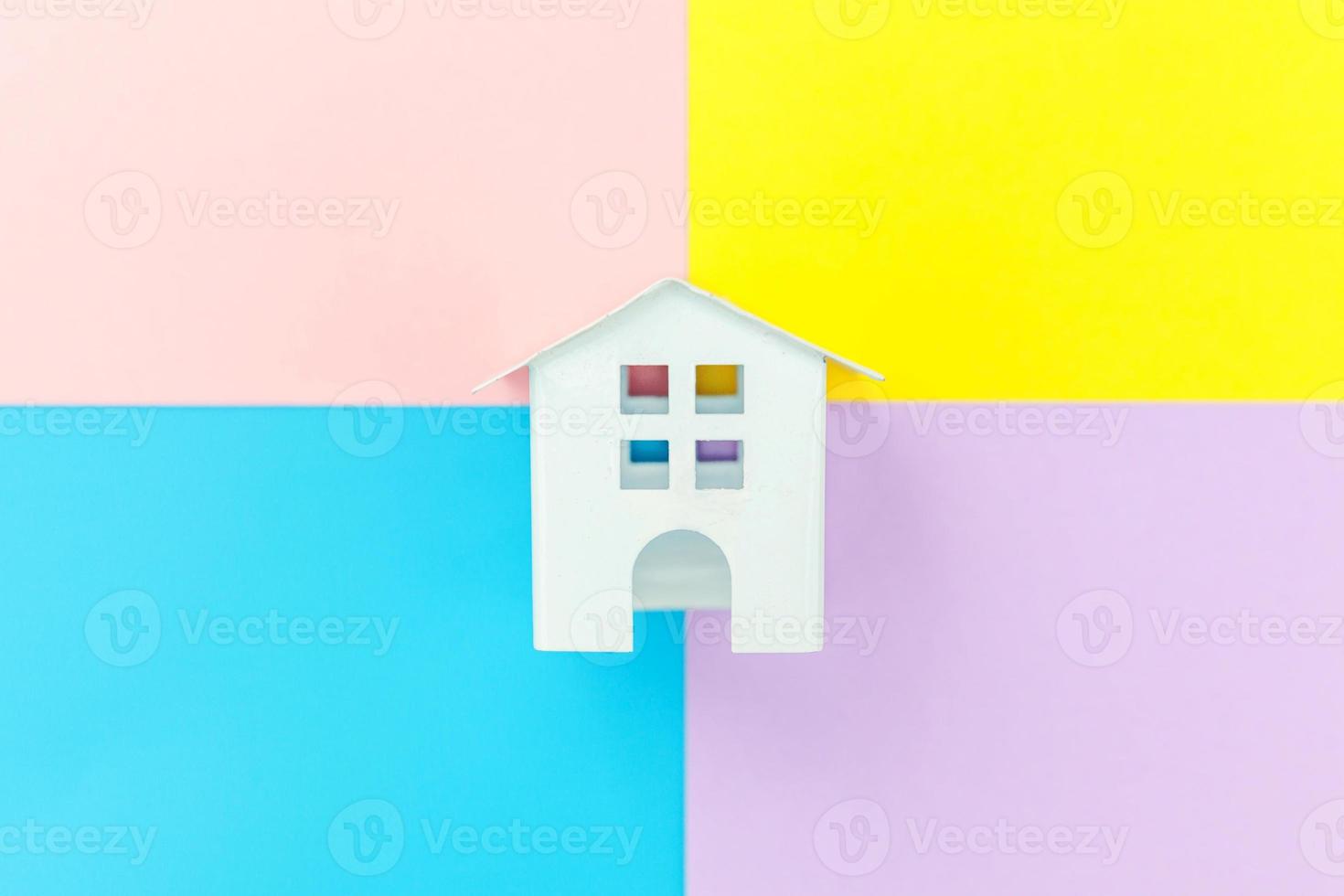 Simply design miniature white toy house isolated on blue yellow pink purple pastel colorful trendy geometric background Mortgage property insurance dream home concept. Flat lay top view copy space. photo