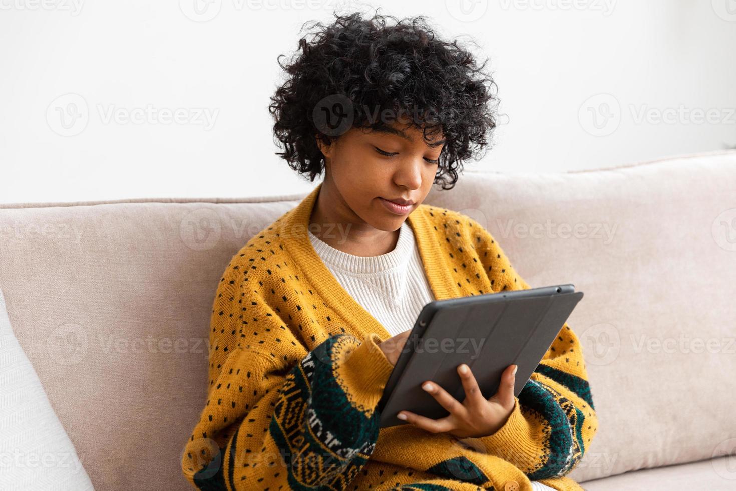 African american girl holding digital tablet touch screen typing scroll page at home. Woman with mobile tech device surfing internet using social media apps playing game. Study work shopping online. photo
