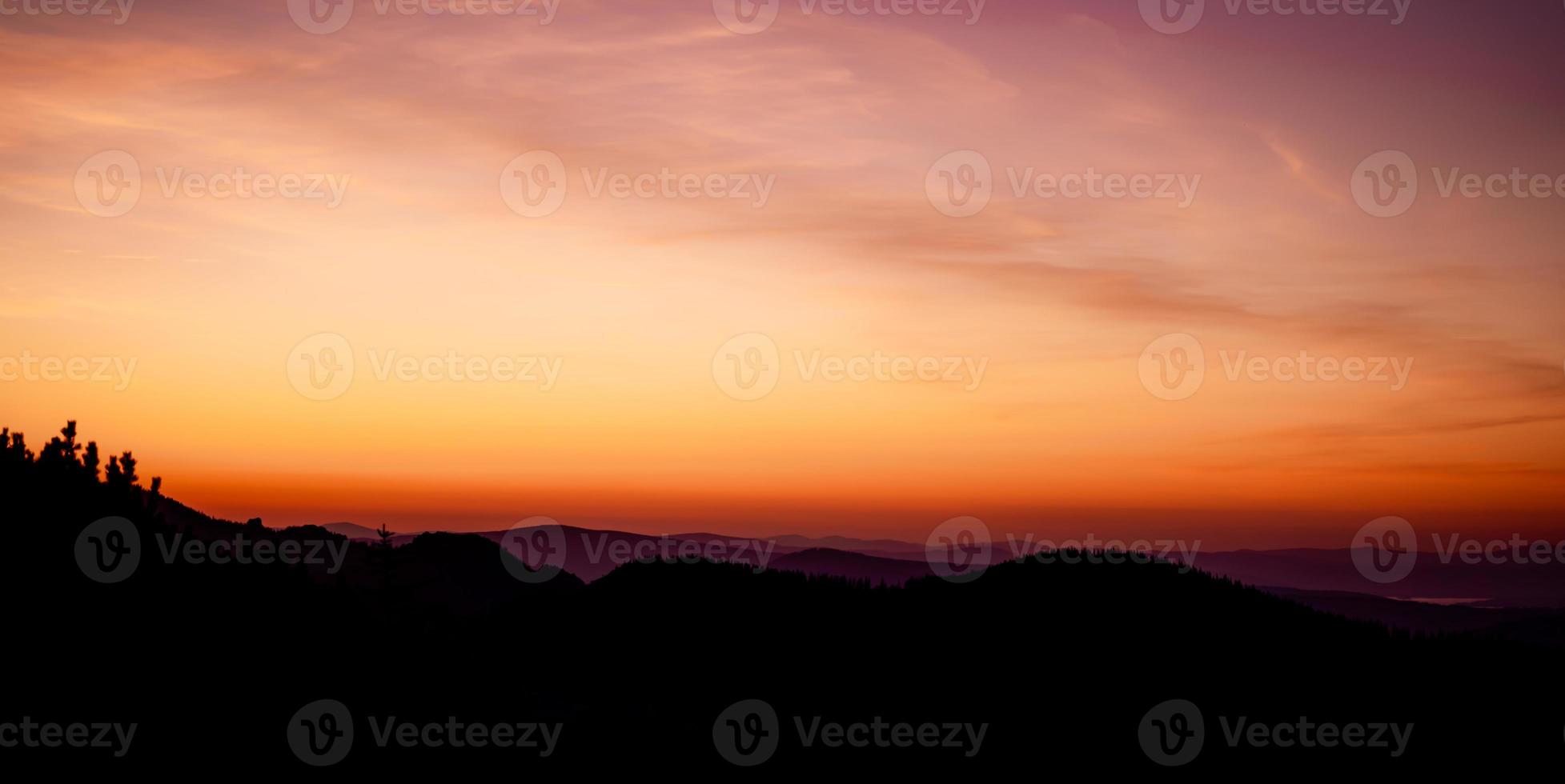 Romantic purple and orange sunset over the high Tatra mountains with dense mist and long sun rays. Vibrant and colorfull sunrise from the peak. Trekking during golden hour in the forest. photo