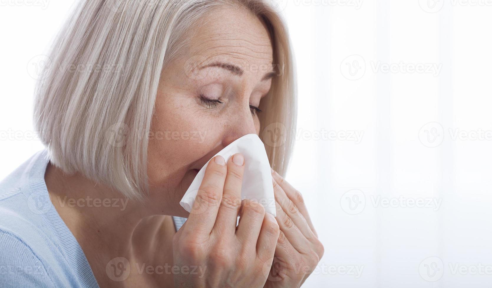 Concept coronavirus, covid-19 respiratory virus with indicating location of the pain. Healthcare, cold, allergy and sick woman blowing her runny nose in paper tissue. photo