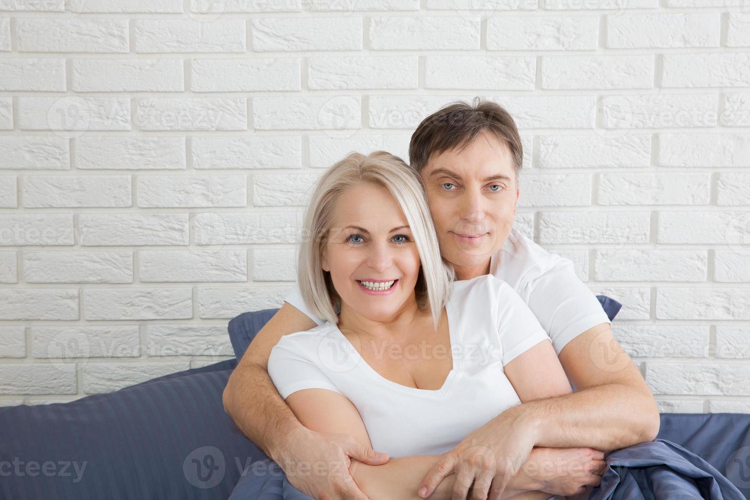 Happy couple is lying in bed together. Enjoying the company of each other. photo