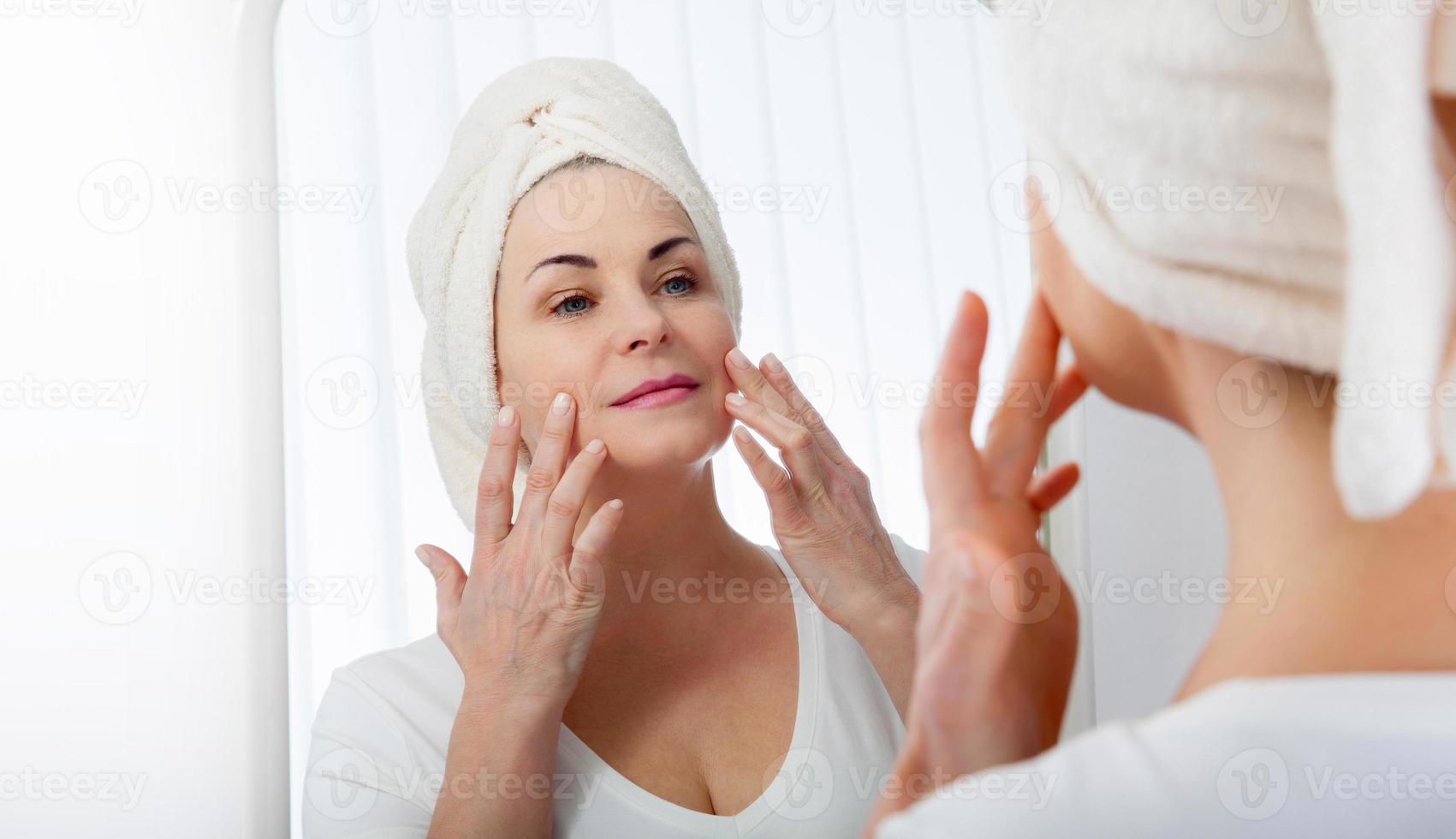 Middle aged woman looking at wrinkles in mirror. Plastic surgery and collagen injections. Makeup. Macro face. Selective focus on the face. photo