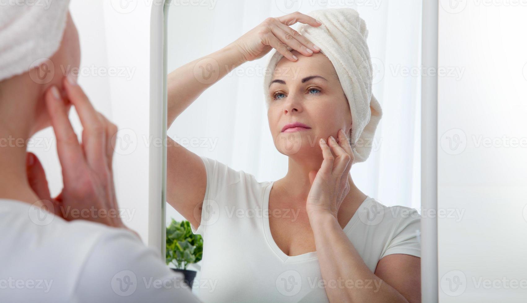 Middle aged woman looking at wrinkles in mirror. Plastic surgery and collagen injections. Makeup. Macro face. Selective focus on the face. photo
