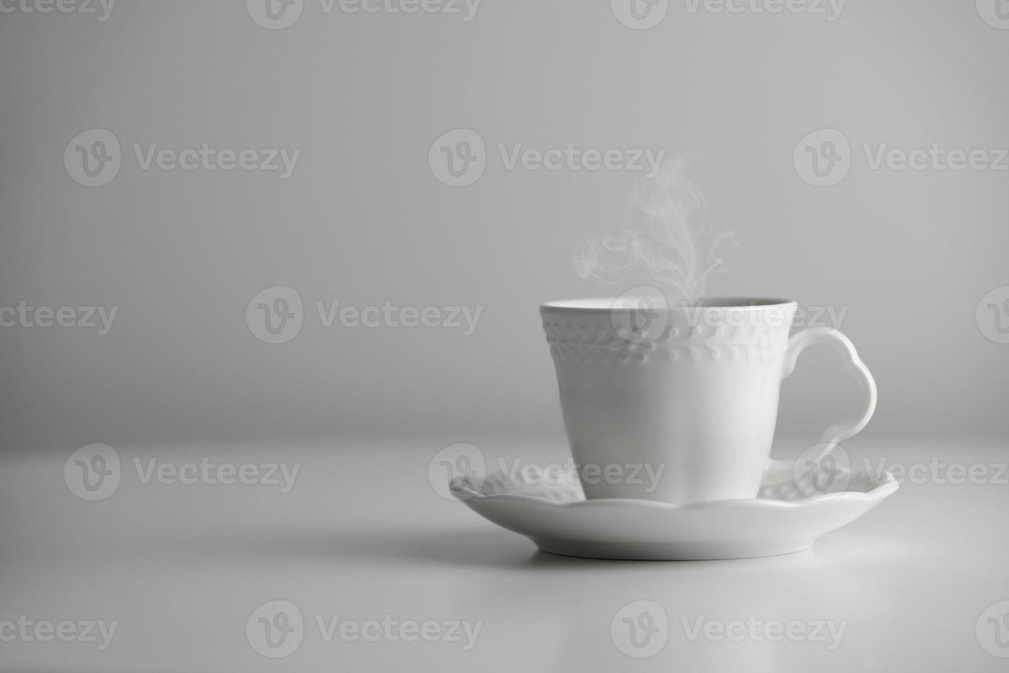 White cup and saucer of tea or coffee with steam on white background. Ceramic cup or mug with hot drink. Mock-up classic porcelain utensils. copy space photo