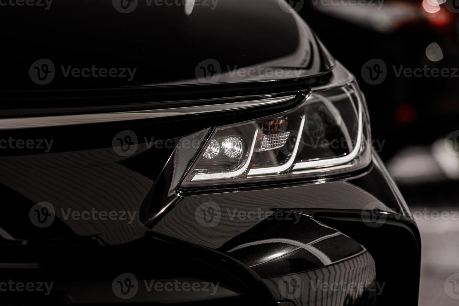 headlight of modern prestigious black car close up. Close up photo of modern car, detail of headlight. Headlight car Projector LED of a modern luxury technology and auto detail