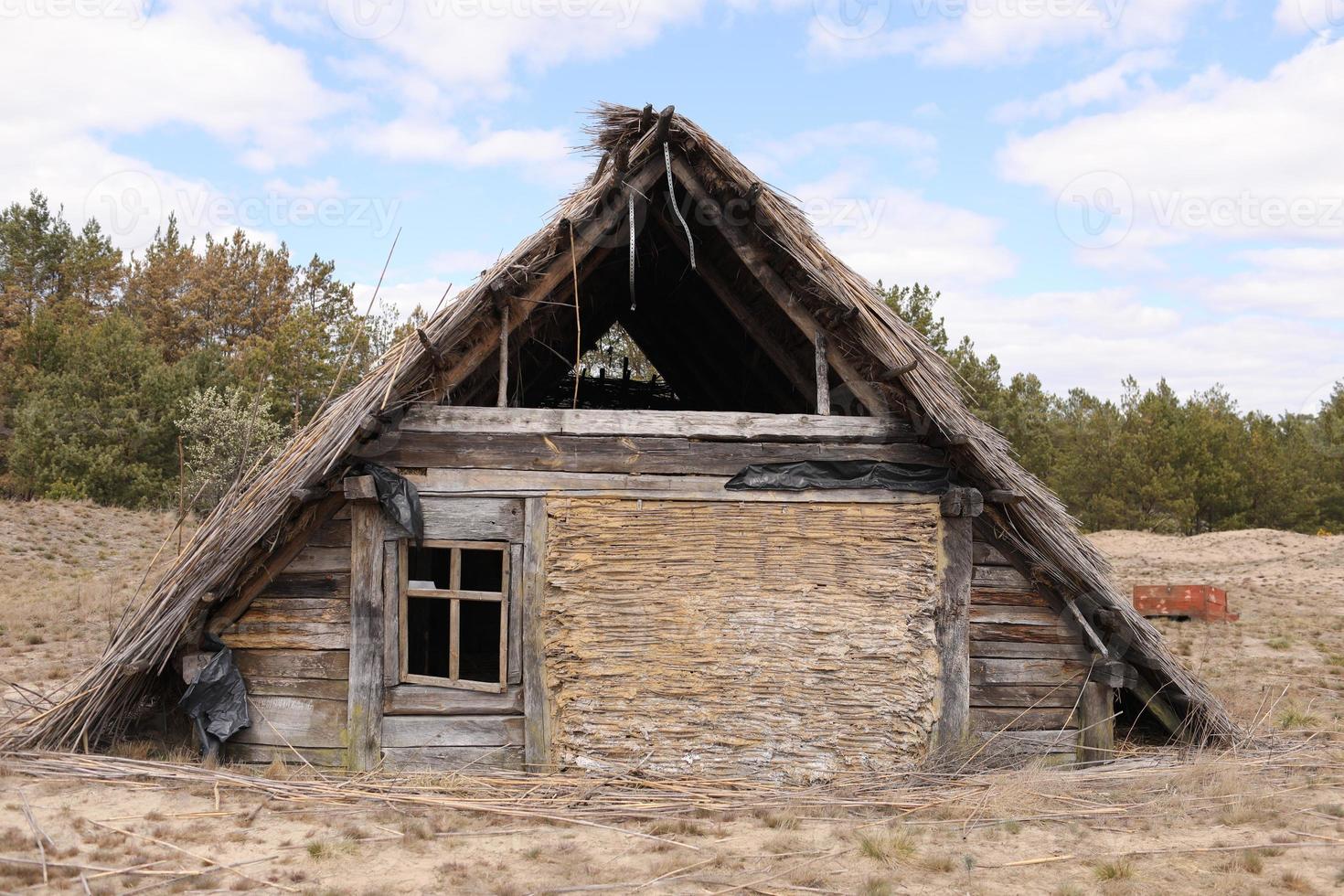traditional old rustic building with a roof covered with straw on early spring day, Ukraine. tourist place photo