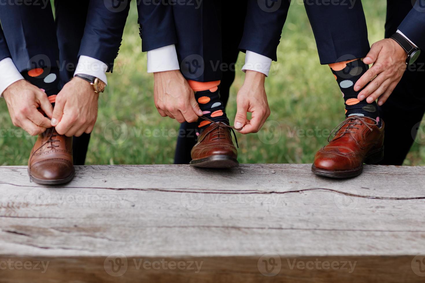The men wears shoes with stylish socks. Stylish suitcase, men's legs, multicolored socks and new shoes. Concept of style, fashion, beauty and vacation. Tie the laces on the shoes. photo