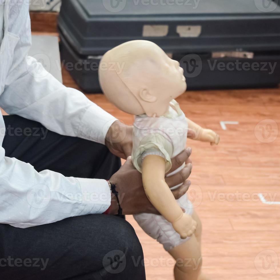 Man performing CPR on baby training doll dummy with one hand compression. First Aid Training - Cardiopulmonary resuscitation. First aid course on CPR dummy, CPR First Aid Training Concept photo