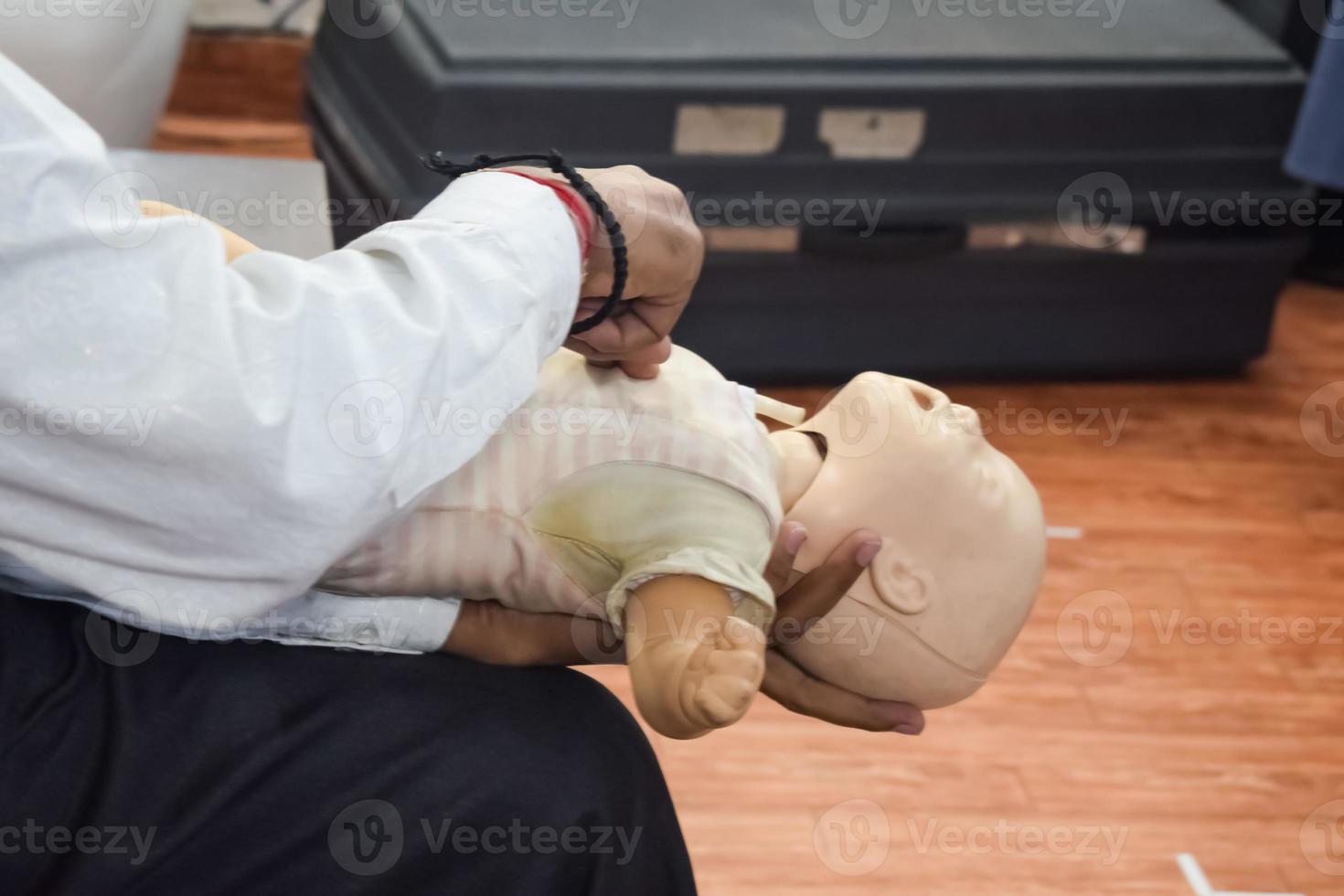 Man performing CPR on baby training doll dummy with one hand compression. First Aid Training - Cardiopulmonary resuscitation. First aid course on CPR dummy, CPR First Aid Training Concept photo