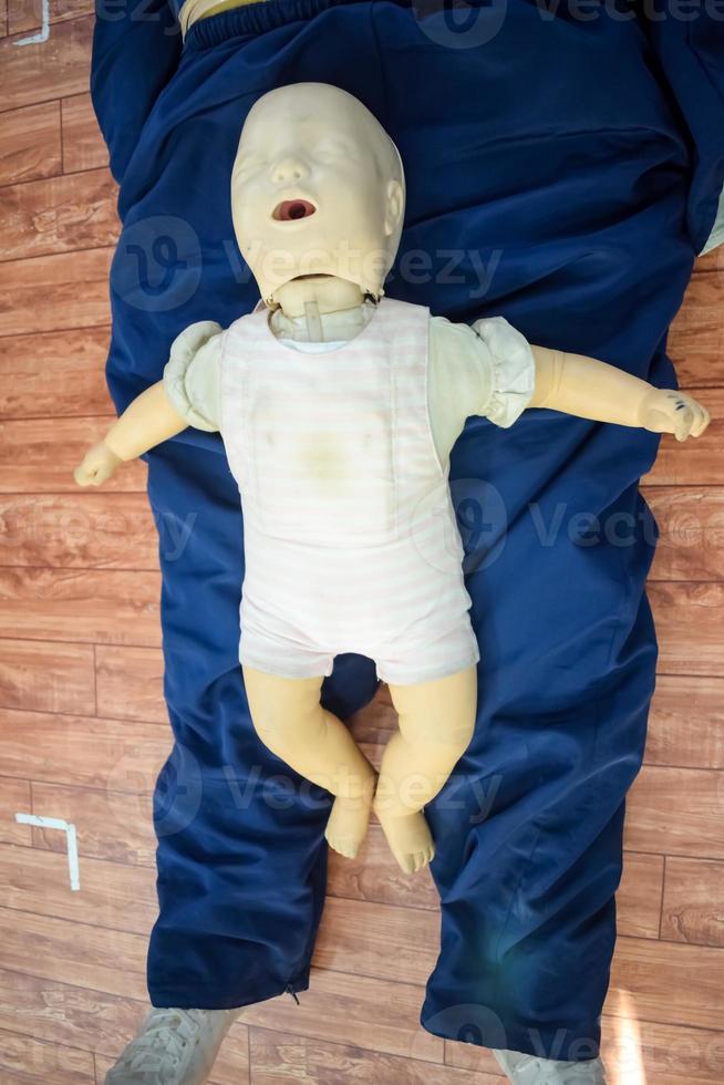 hombre realizando RCP en un maniquí de muñeca de entrenamiento para bebés con compresión con una mano. formación en primeros auxilios - reanimación cardiopulmonar. curso de primeros auxilios en maniquí de cpr, concepto de capacitación en primeros auxilios de cpr foto